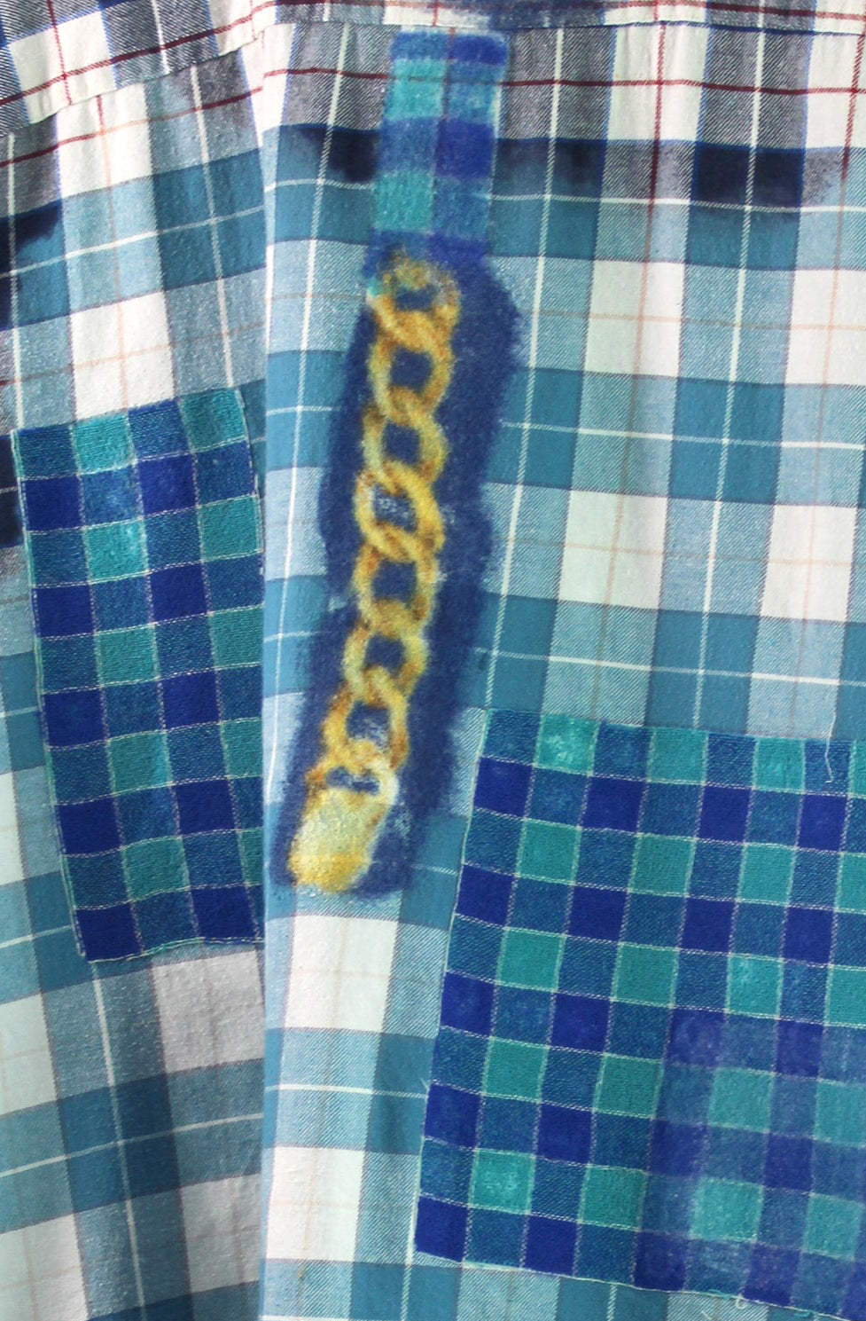 Plaid shirt with chain designs on a hanger against a white background