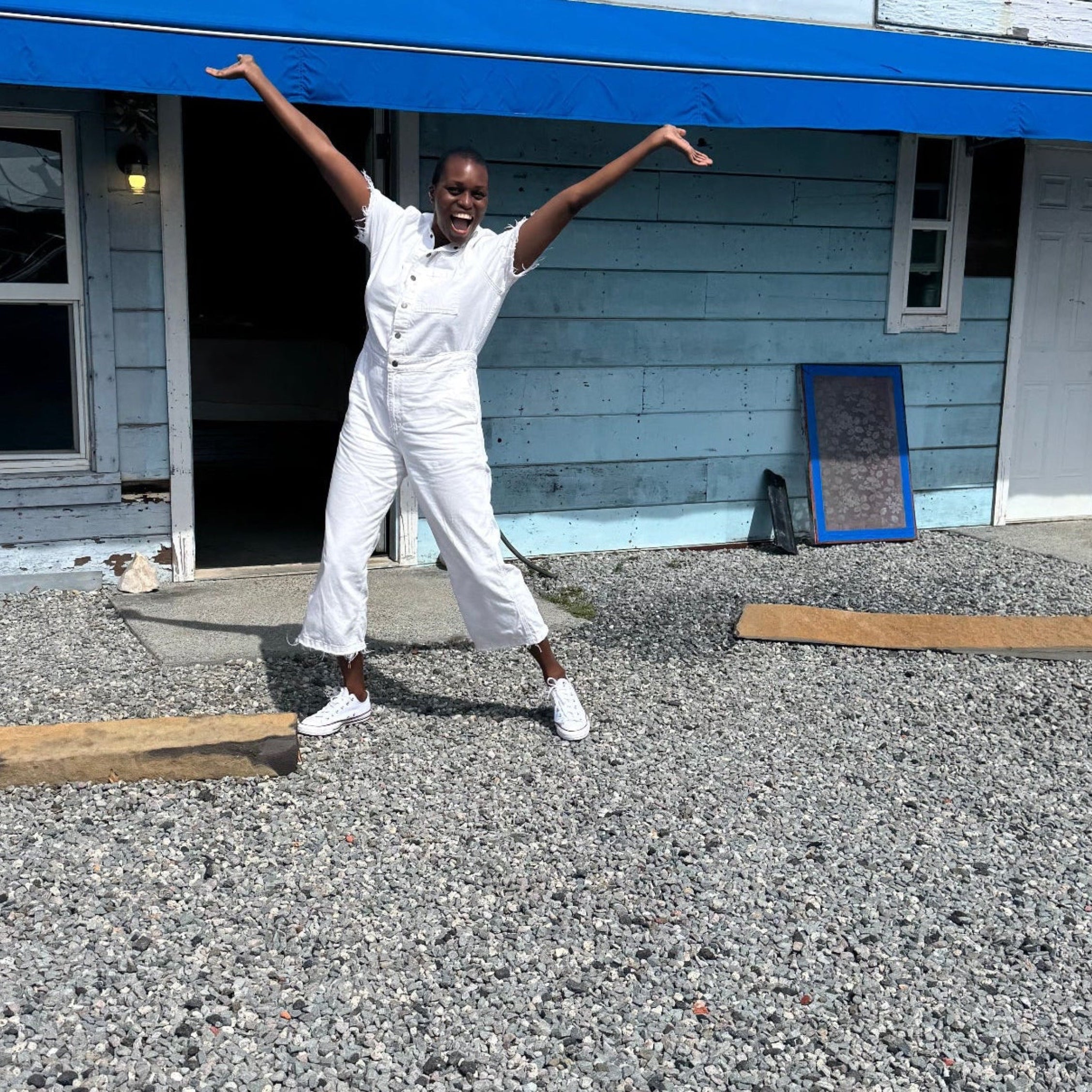 Person in white outfit standing on a blue pool deck with a building in the background